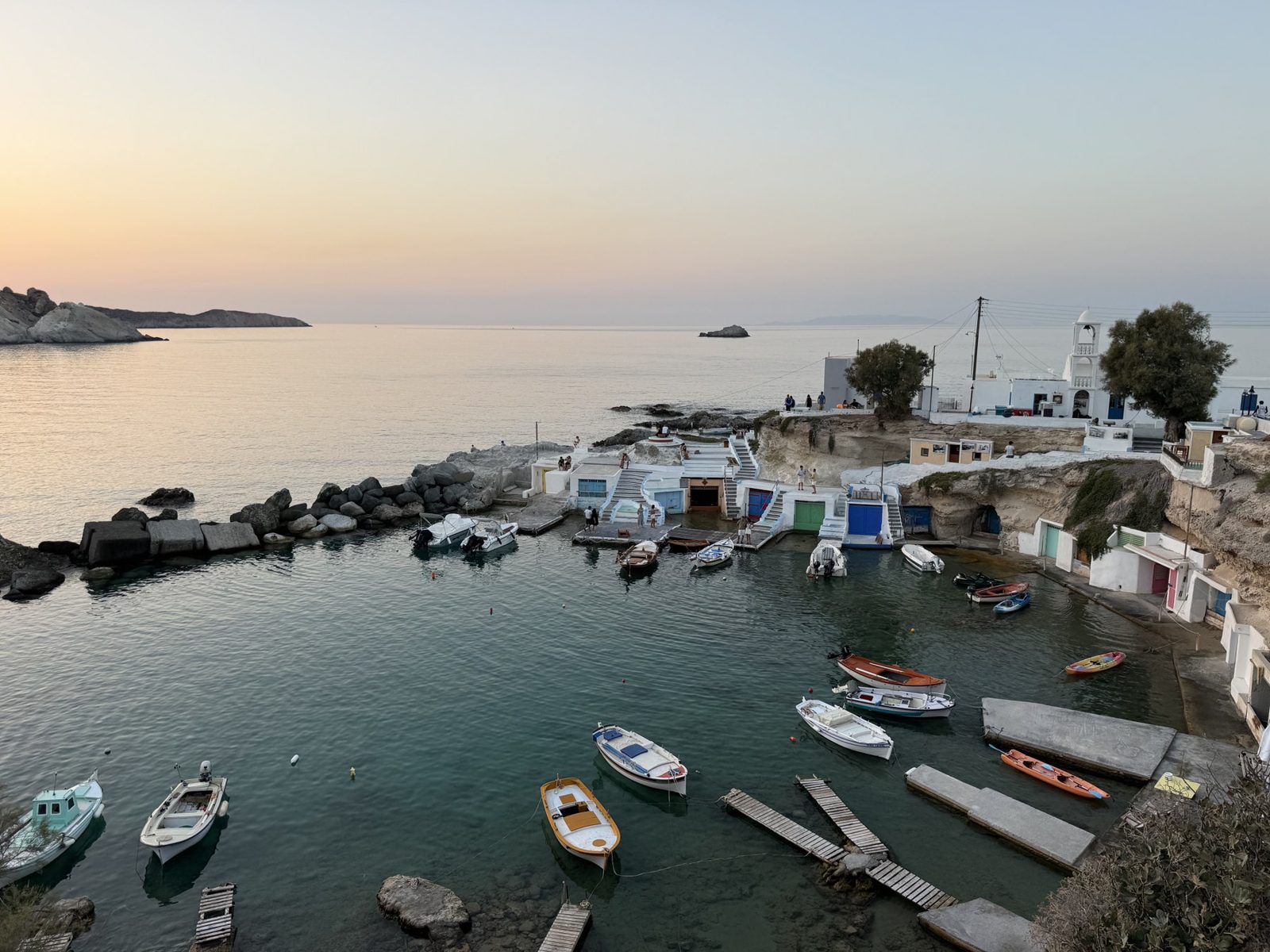 Greek island fishing village with boats moored in a calm harbor at sunset