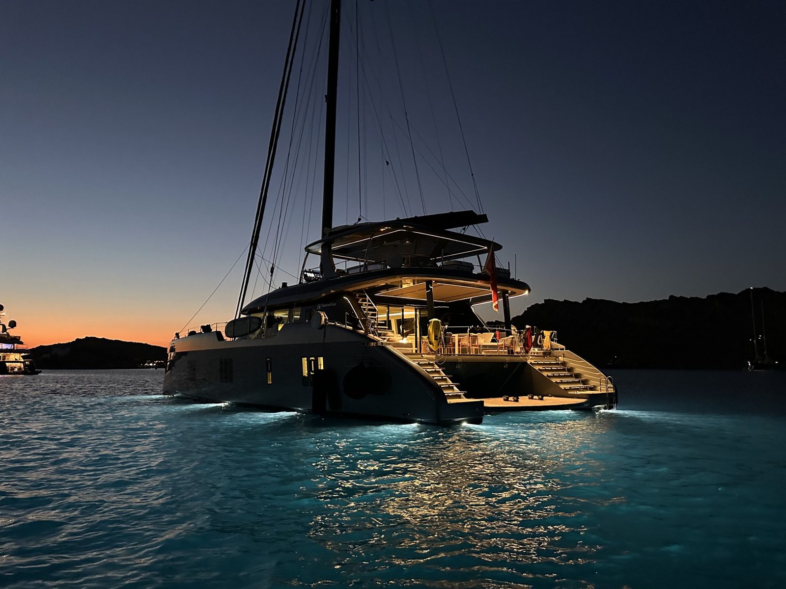 Luxury sailing catamaran lit up at anchor after sunset