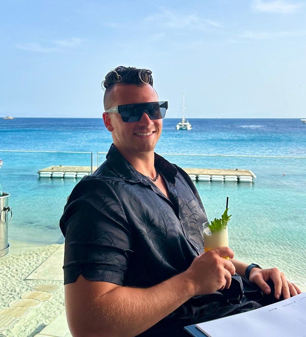 Terry at a seaside restaurant overlooking clear blue water